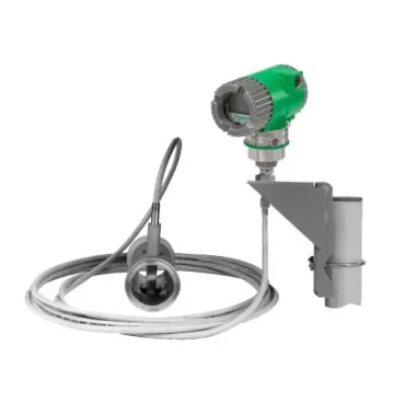 An insertion-style vortex flow meter, showing the sensor head connected via a long cable to a remote-mounted green transmitter unit on a mounting bracket.